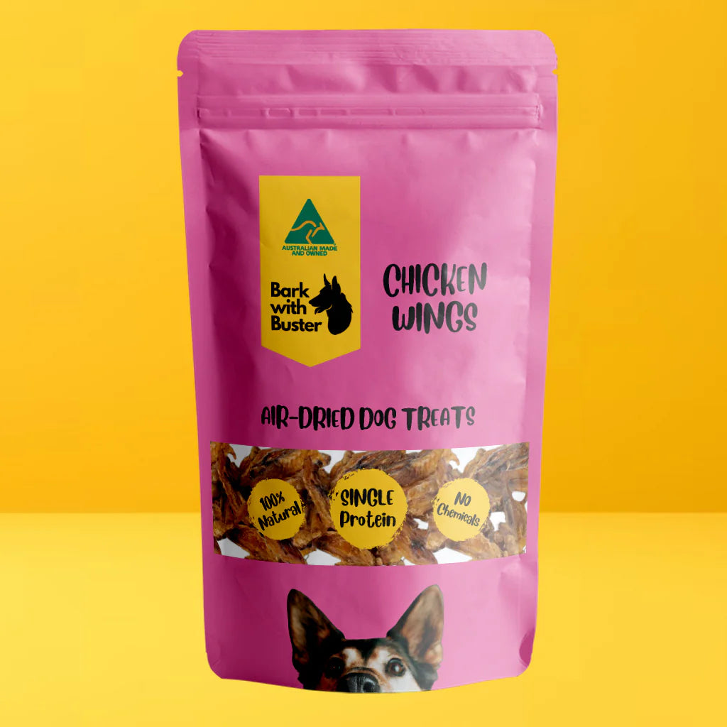 Pink package of Bark with Buster Chicken Wings dog treats on a yellow background