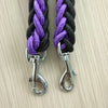 Two braided black and purple dog leashes with metal clasps on a light wooden surface.
