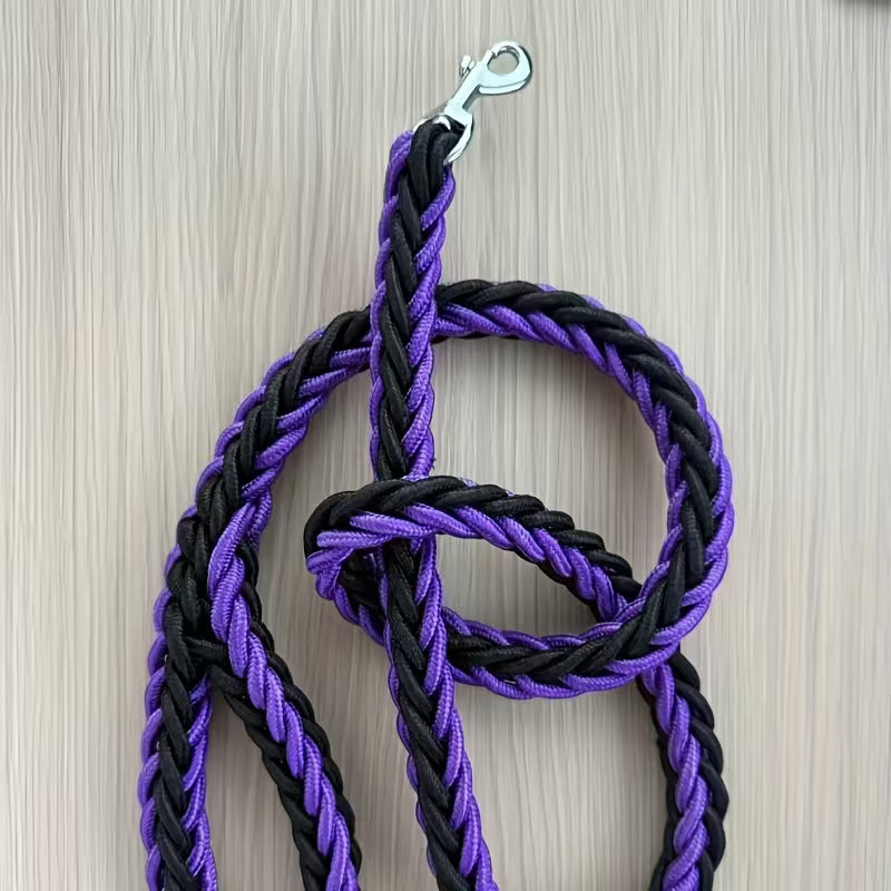 Black and purple braided rope leash with a metal clip on a wooden surface