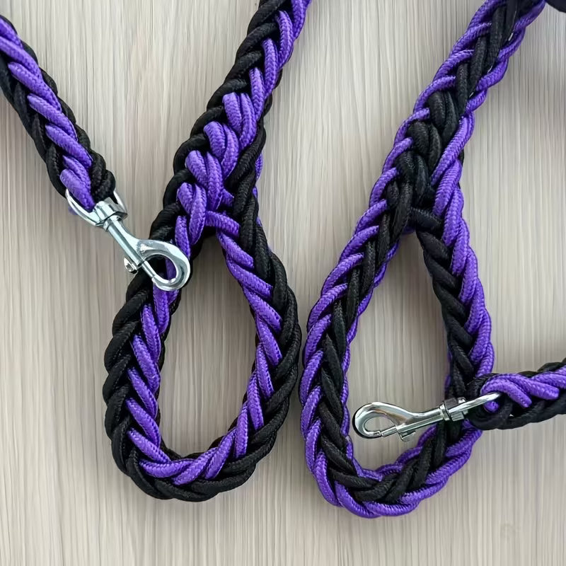 Black and purple braided dog leashes with metal clasps on a light wood background