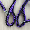 Black and purple braided dog leashes with metal clasps on a light wood background